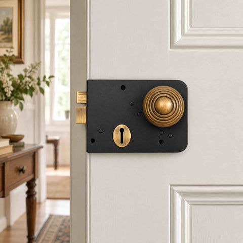 Black and antique brass Right Hand Scotch rim lock with 50mm beehive door knob fitted to a white internal door
Close-up