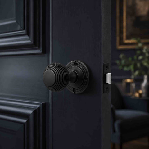 Black sprung beehive mortice door knob fitted to a dark panelled interior door