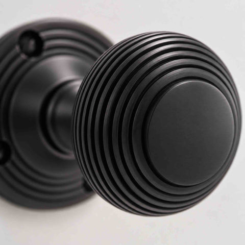 Close-up of black beehive door knob showing traditional reeded detailing