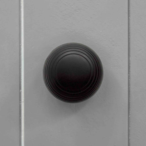 Front view of black reeded beehive door knob fitted to a grey internal door