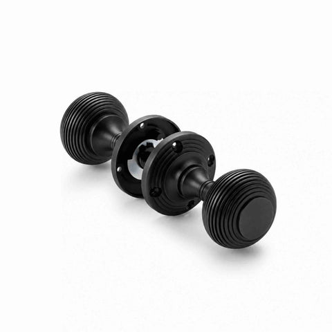 Pair of black sprung beehive mortice door knobs showing attached backplates