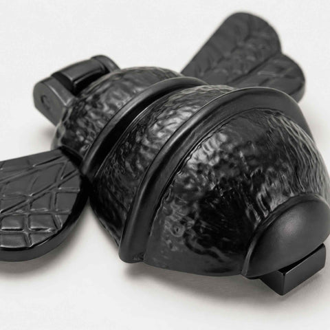 Macro view of black cast iron bumble bee door knocker highlighting textured body and wing detailing