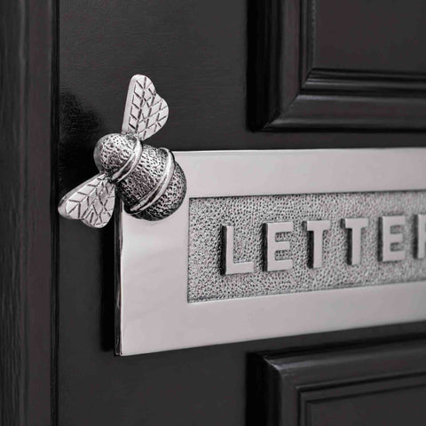 Close-up of polished chrome Bumble Bee "LETTERS" letter plate fitted to a black front door