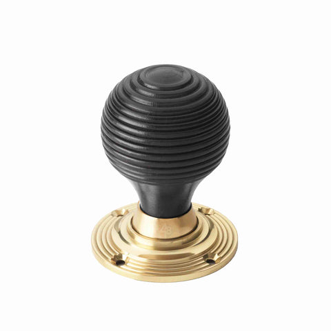 Single ebonised black beehive rim mortice door knob with an unlacquered polished brass backplate on a white background.