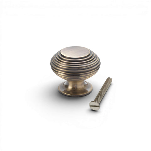 Large antique brass beehive cupboard knob with fixing screw, solid brass cabinet knob with reeded design on white background