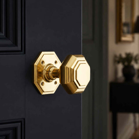 Polished brass octagonal door knob fitted to a dark interior door with matching octagonal rose.
