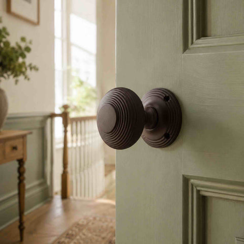 Matt Antique Beehive Mortice Door Knob fitted to a sage green door.
