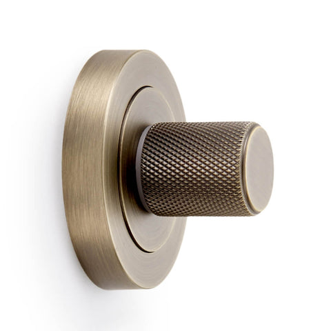 Close-up of matt antique brass knurled thumb turn showing textured grip and round rose