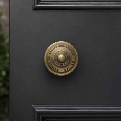 Matt antique brass reeded door knob fitted to a black panelled door