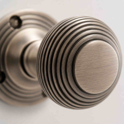 Macro close-up of a matt antique brass beehive door knob showing the traditional reeded detailing and brushed finish.