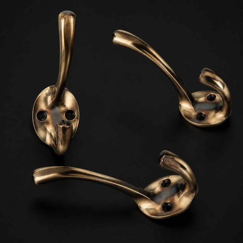 Pack of 3 Unlacquered Aged Brass Victorian Coat Hooks Displayed on Dark Background