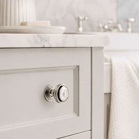 Large polished nickel Bloxwich cupboard knob fitted to a white shaker-style bathroom vanity drawer, creating a bright, classic finish.