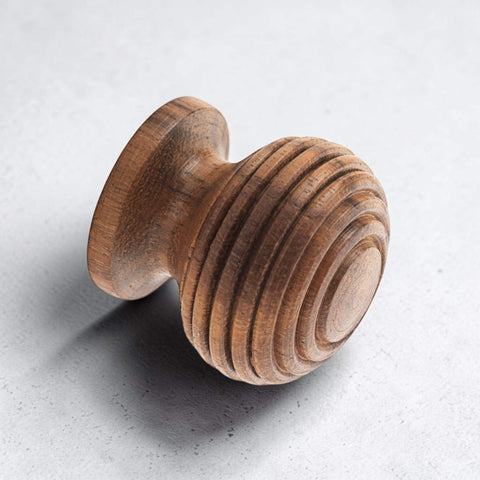 Angled close-up of traditional rosewood beehive cupboard knob on textured surface