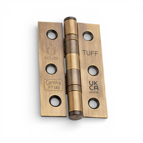 Close-up of an aged brass CE7 ball bearing butt hinge with UKCA and Certifire fire-rated markings