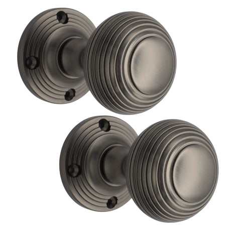 Close up of pewter beehive mortice door knob highlighting concentric ridged design and fixing points on circular backplate.