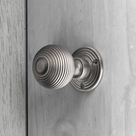 Pewter reeded beehive mortice door knob fitted to a painted wooden door.