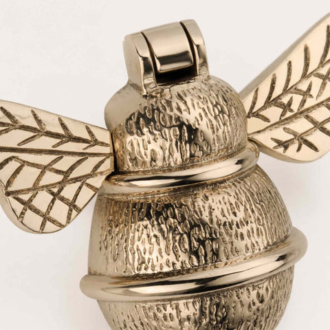 Close-up of polished brass bumble bee door knocker showing textured body and wing detailing