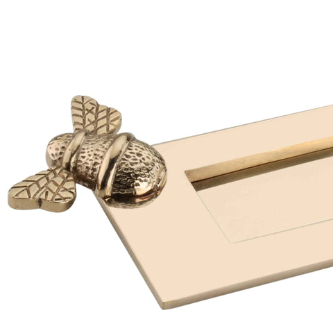 Close-up of decorative bumble bee detailing on unlacquered polished brass letter plate