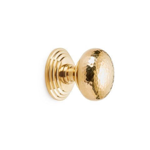 Hammered polished brass cottage centre door knob with stepped circular backplate, side profile on white background