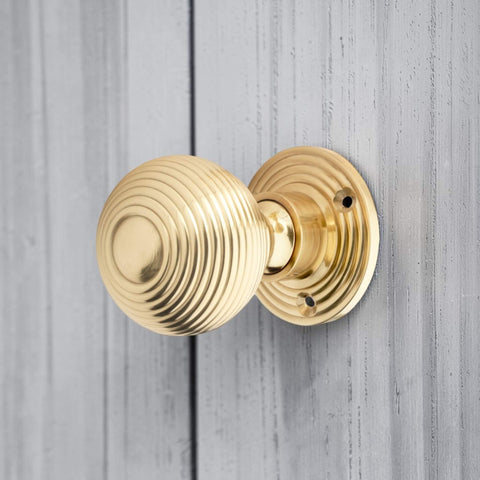 Polished Brass Hollow Beehive Door Knob Installed on Grey Wooden Door