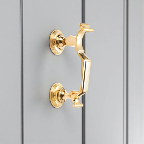 Unlacquered polished brass reeded doctor door knocker side view fitted to grey door