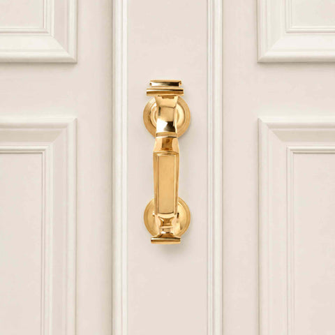 Polished brass reeded doctor door knocker fitted to a cream panelled front door, highlighting the traditional design and polished finish.