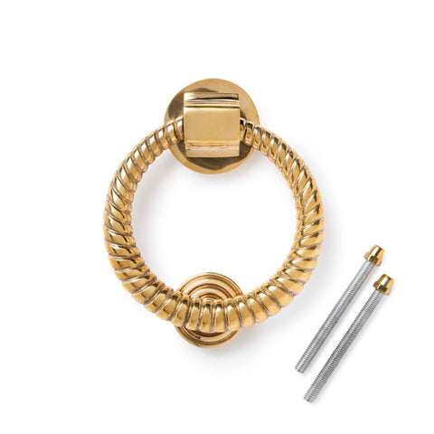 Polished brass reeded ring door knocker with supplied fixing bolts on a white background