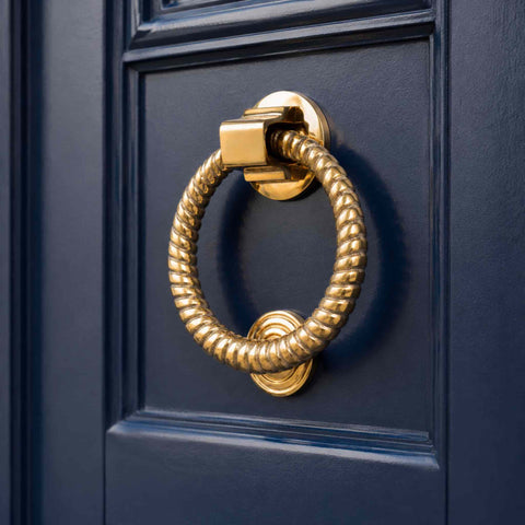 Polished brass reeded ring door knocker installed on a dark blue front door