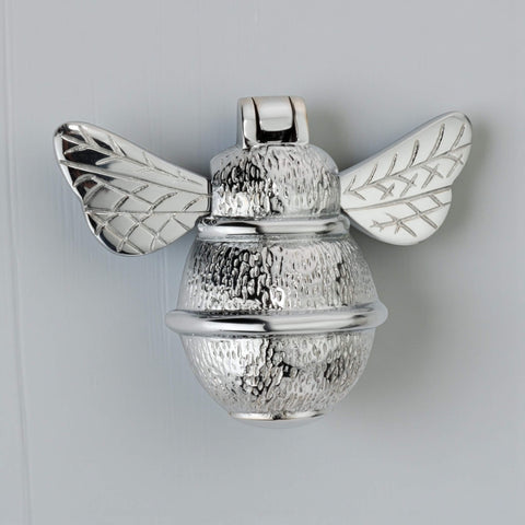 Solid brass bumble bee door knocker in polished chrome finish, front view showing reflective surface and detailed wings on grey door.
