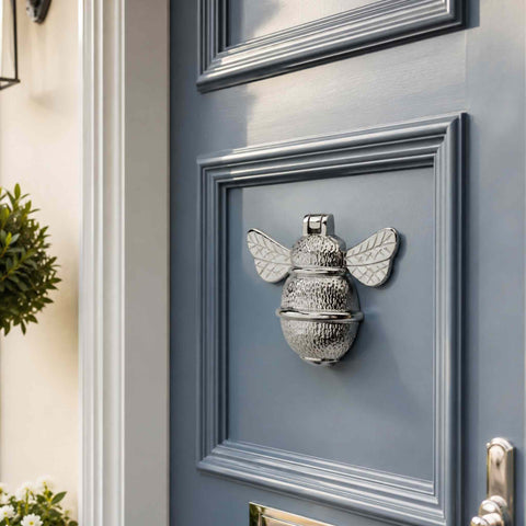 Polished Chrome Bumble Bee Door Knocker installed on a blue-grey front door with decorative moulded panels