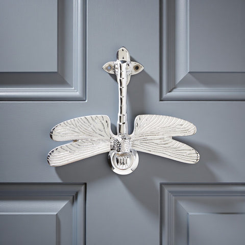 Polished chrome dragonfly door knocker fitted to a grey front door.