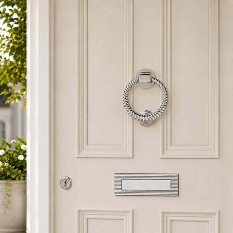 Polished chrome reeded ring door knocker installed on a cream front door with matching letter plate