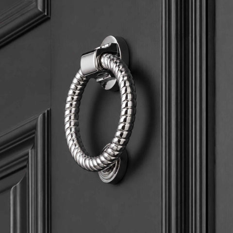 Polished chrome reeded ring door knocker mounted on a dark grey front door