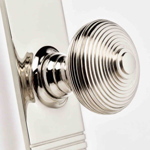 Macro close-up of a solid brass polished nickel beehive door knob showing the traditional concentric reeded detailing and tall backplate.