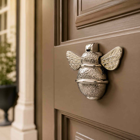 Polished nickel bumble bee door knocker fitted to a warm taupe front door