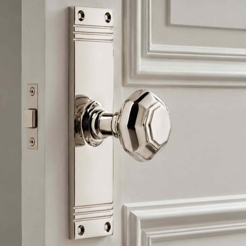 Polished nickel octagonal door knob on tall backplate fitted to a white panelled door with mortice latch visible