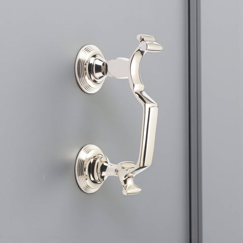 Polished nickel reeded doctor door knocker mounted on grey door, angled side view showing circular backplates and smooth reflective finish.