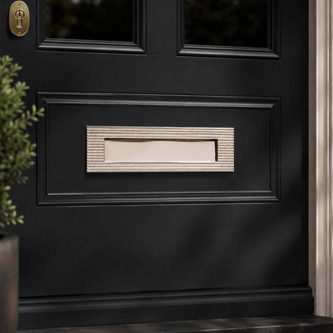 Polished nickel reeded solid brass letter box plate installed on a black front door