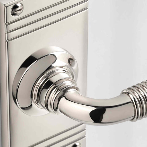Detailed close-up of the polished nickel reeded lever handle showing the smooth curved lever and precision-machined reeded grip.
