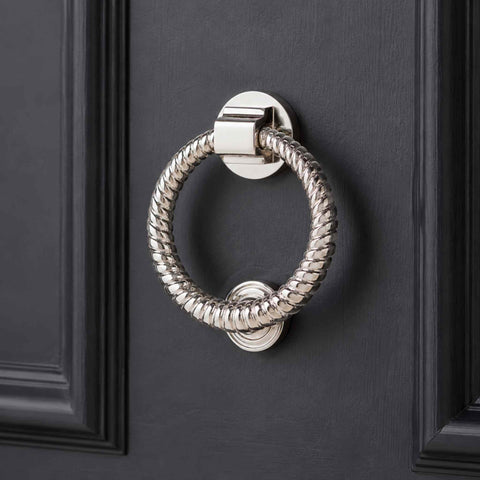 Close-up of polished nickel reeded ring door knocker mounted on a dark front door
