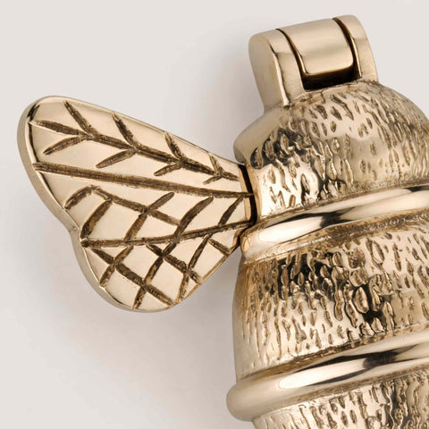 Close-up of unlacquered polished brass bumble bee door knocker showing detailed wing engraving