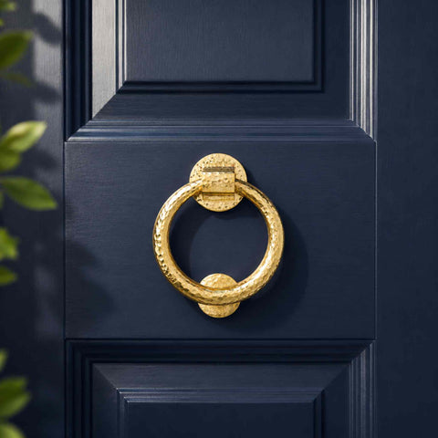 Close-up of polished brass hammered ring door knocker showing the detailed hammered texture and solid brass construction.