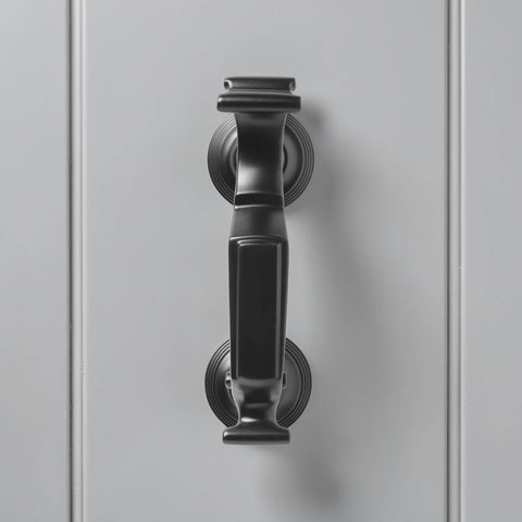 Front view of powder coated black reeded doctor door knocker on grey door, displaying traditional shape and ribbed backplates.