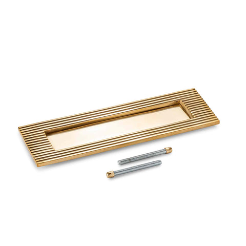 Reeded aged solid brass letter box plate with fixing bolts on a white background