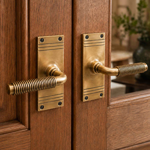 Pair of antique brass reeded lever door handles fitted to timber glazed doors, showing the elegant traditional styling and reeded detailing.