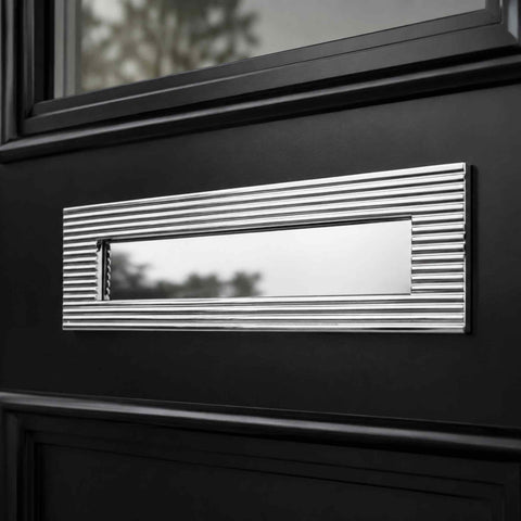 Polished chrome reeded letter box plate installed on a black front door