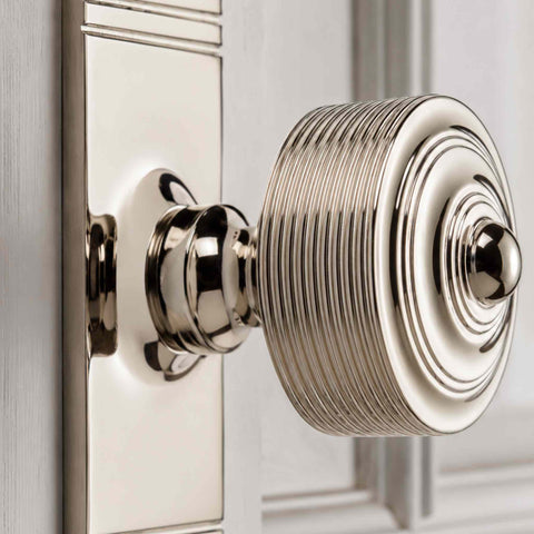 Close-up of a reeded polished nickel door knob showing the detailed concentric face, polished finish and finely reeded edge.