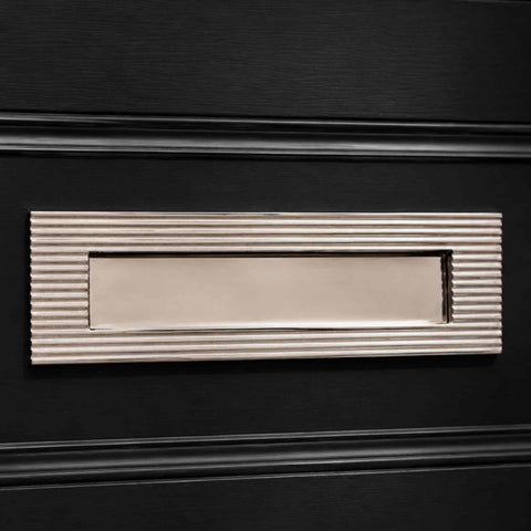 Close-up of polished nickel reeded frame and plain sprung flap letter box plate