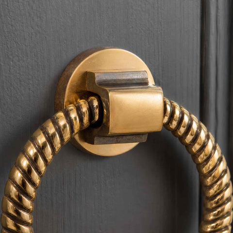 Close-up of aged brass reeded ring door knocker on dark painted door