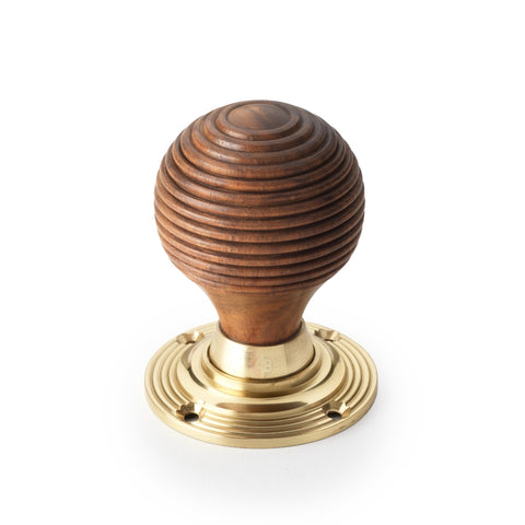 Single rosewood beehive door knob with polished brass rose on white background
